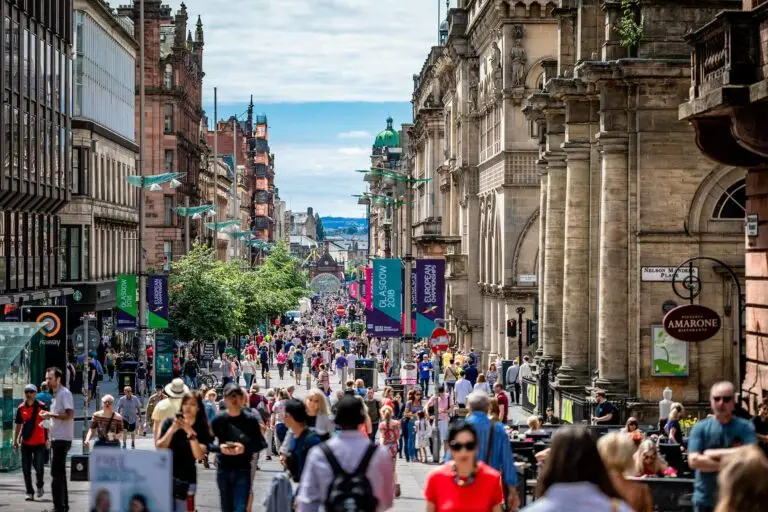 Busy Buchanan Street in Glasgow City Centre, Scotland, with crowds of people shopping and historic architecture lining the bustling pedestrian area