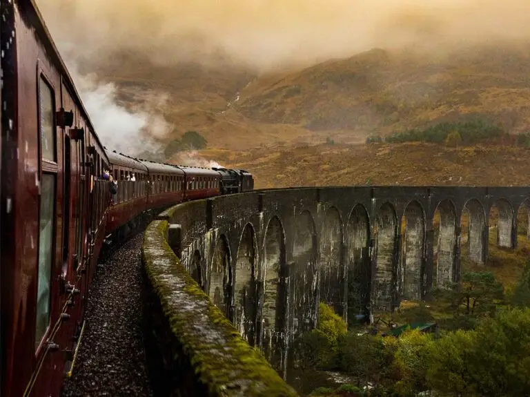Steam train crossing the Glenfinnan Viaduct in the Scottish Highlands, famous for Harry Potter tours and scenic Scotland railway journeys