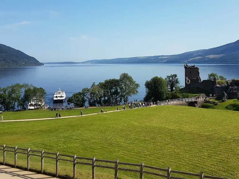 Urquhart Castle overlooking Loch Ness in Scotland with tourists exploring the historic ruins and scenic landscape