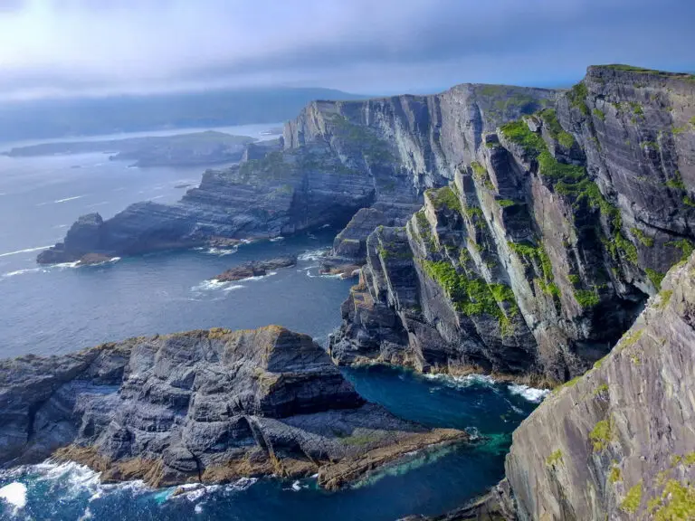 Dramatic coastal cliffs along the Ring of Kerry in Ireland with rugged rock formations and Atlantic Ocean views, a popular sightseeing destination for tourists.