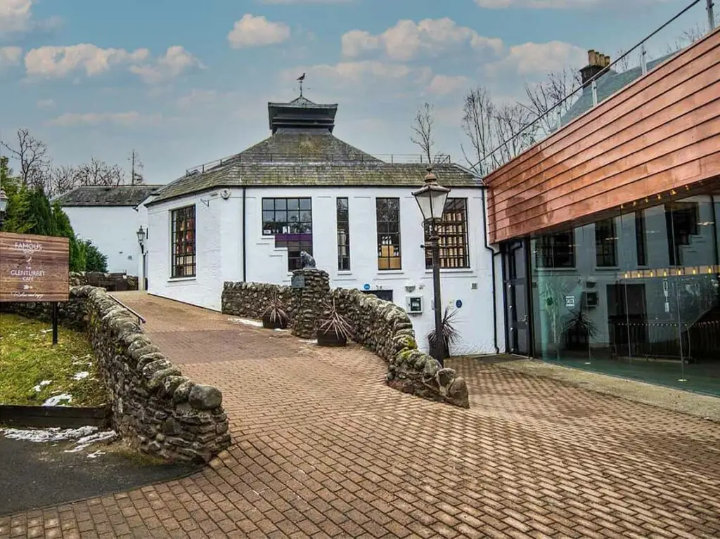 Glenturret Distillery in the Highlands of Scotland, home of the Famous Grouse, featuring historic white buildings and cobbled pathway at a popular Scottish whisky tourism destination