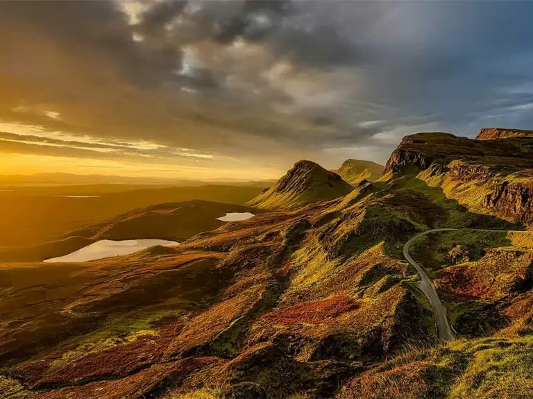 Sunset view of the Quiraing on the Isle of Skye in Scotland, showcasing dramatic cliffs, winding road, and rugged Highland landscape ideal for sightseeing tours.