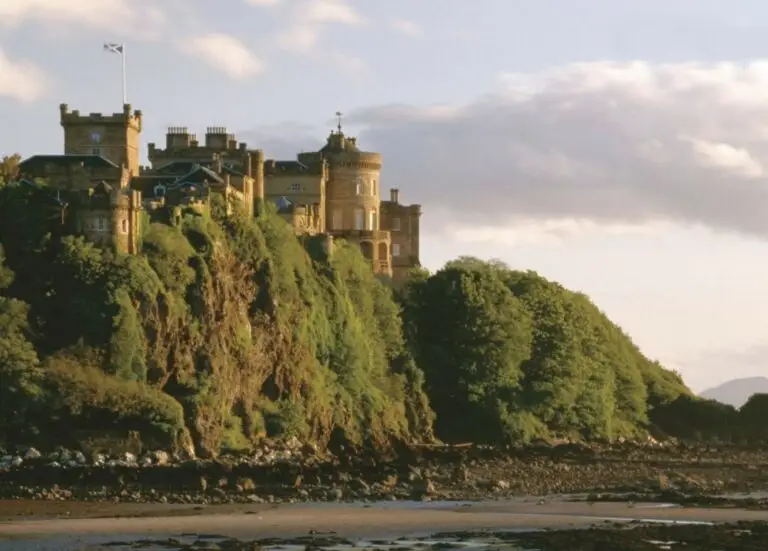 Culzean Castle perched on a clifftop overlooking the coastline in Ayrshire, Scotland, surrounded by lush greenery and scenic seaside landscape.
