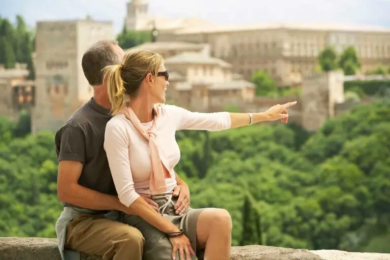 Middle aged couple sightseeing and pointing towards Alhambra Palace in Granada Spain during a scenic tour