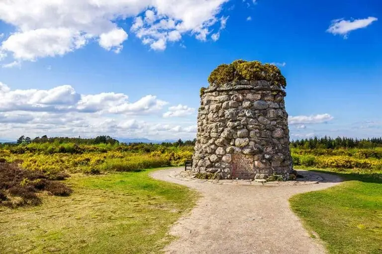 Culloden Battlefield memorial cairn surrounded by scenic countryside under a blue sky in Scotland