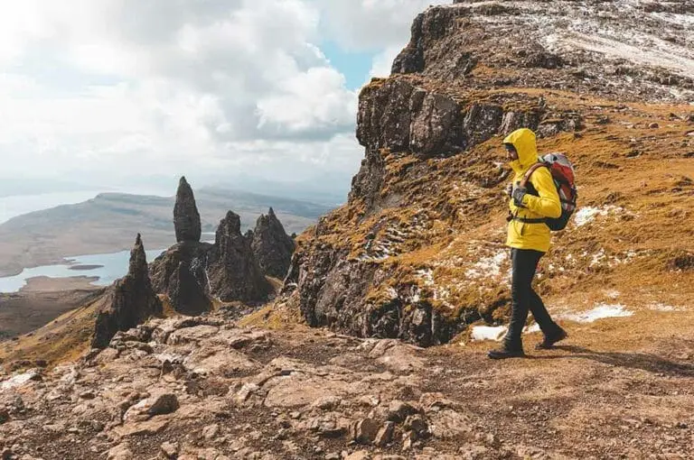 Hiker exploring the Old Man of Storr on the Isle of Skye in Scotland, with dramatic rock formations and scenic mountain landscape views