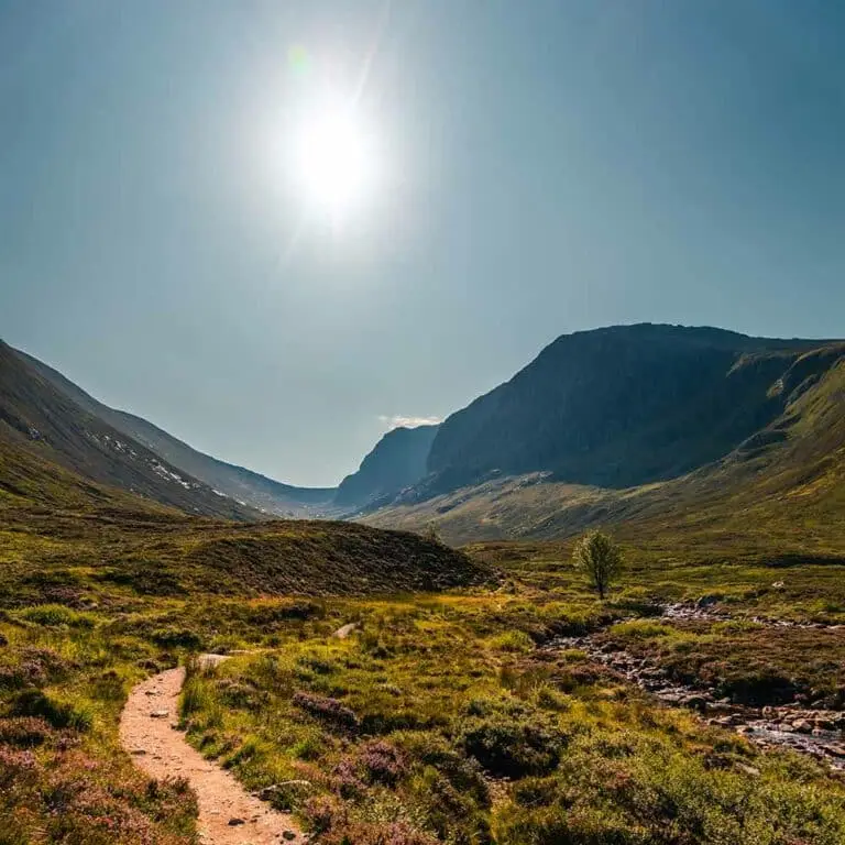 Scenic view of Ben Nevis Walking Trail in the Scottish Highlands with mountains, sunlight, and greenery, popular hiking tour destination in Scotland