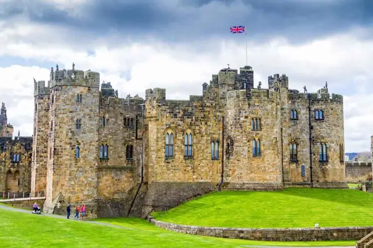 Alnwick Castle in Northumberland England with tourists exploring the historic medieval fortress and gardens on a guided tour