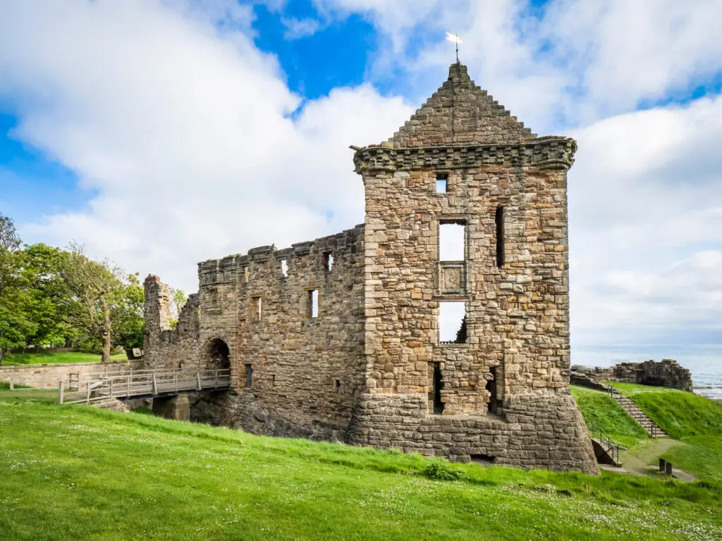 Historic ruins of St Andrews Castle overlooking the North Sea in St Andrews, Scotland, with stone walls, green grass, and blue sky, popular tourist attraction on Scottish tours.