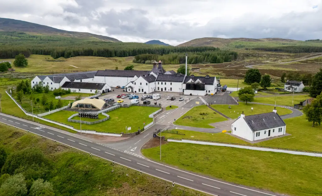 Aerial view of Dalwhinnie Distillery in the Scottish Highlands surrounded by rolling hills and greenery, popular whisky distillery and tourist attraction in Scotland