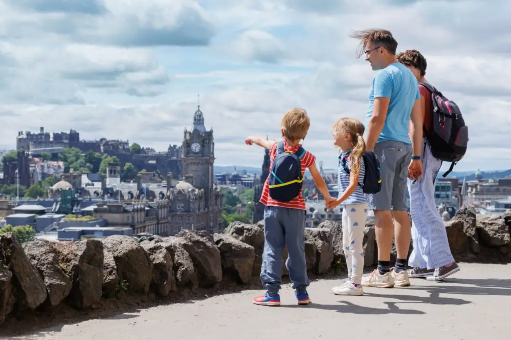 Family enjoying panoramic view of Edinburgh, Scotland with Edinburgh Castle and city skyline in the background during a sightseeing tour
