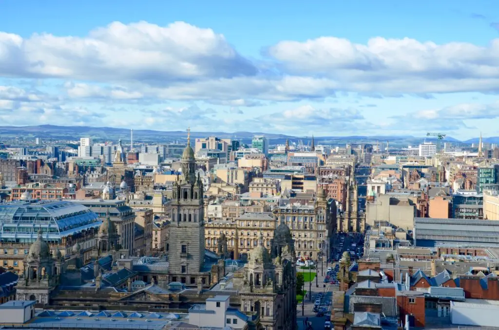 Panoramic view of Glasgow cityscape in Scotland featuring historic architecture, modern buildings, and scenic skyline under blue skies