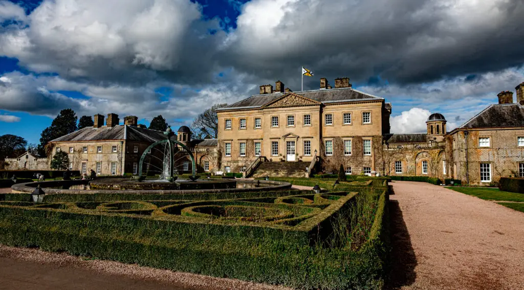 Historic Dumfries House in Ayrshire Scotland with landscaped gardens and fountain under dramatic sky