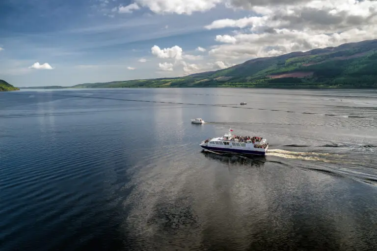 Tour boat cruising on Loch Ness surrounded by scenic Highlands landscape in Scotland