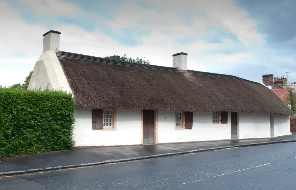 Traditional whitewashed thatched cottage in Alloway, Scotland, a popular historic site featured on Braw Scottish Tours