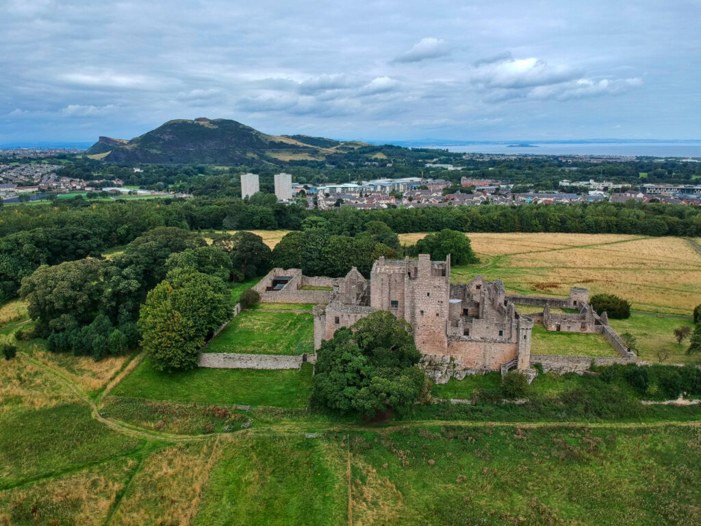 Aerial view of Craigmillar Castle in Edinburgh, Scotland, surrounded by green countryside and historic landscape, popular tourist attraction on Braw Scottish Tours