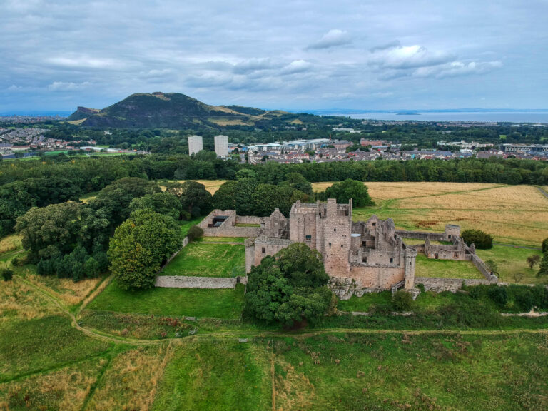 Aerial view of Craigmillar Castle in Edinburgh, Scotland, surrounded by green countryside and historic landscape, popular tourist attraction on Braw Scottish Tours