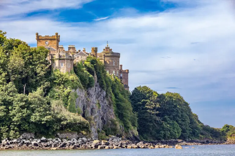Culzean Castle perched on a cliff overlooking the sea in Ayrshire, Scotland, surrounded by lush greenery and blue sky, a popular Scottish tourist attraction and historic site