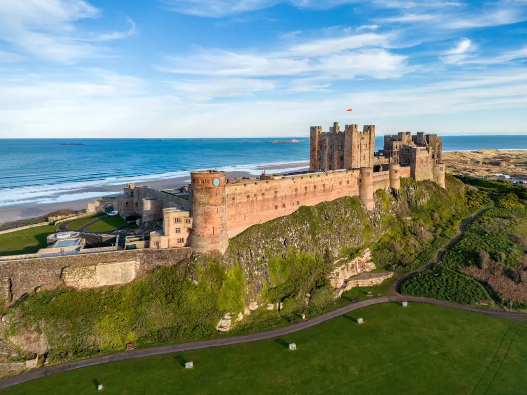 Aerial view of Bamburgh Castle in Northumberland, England overlooking the North Sea coastline, a popular historic attraction featured on Braw Scottish Tours.