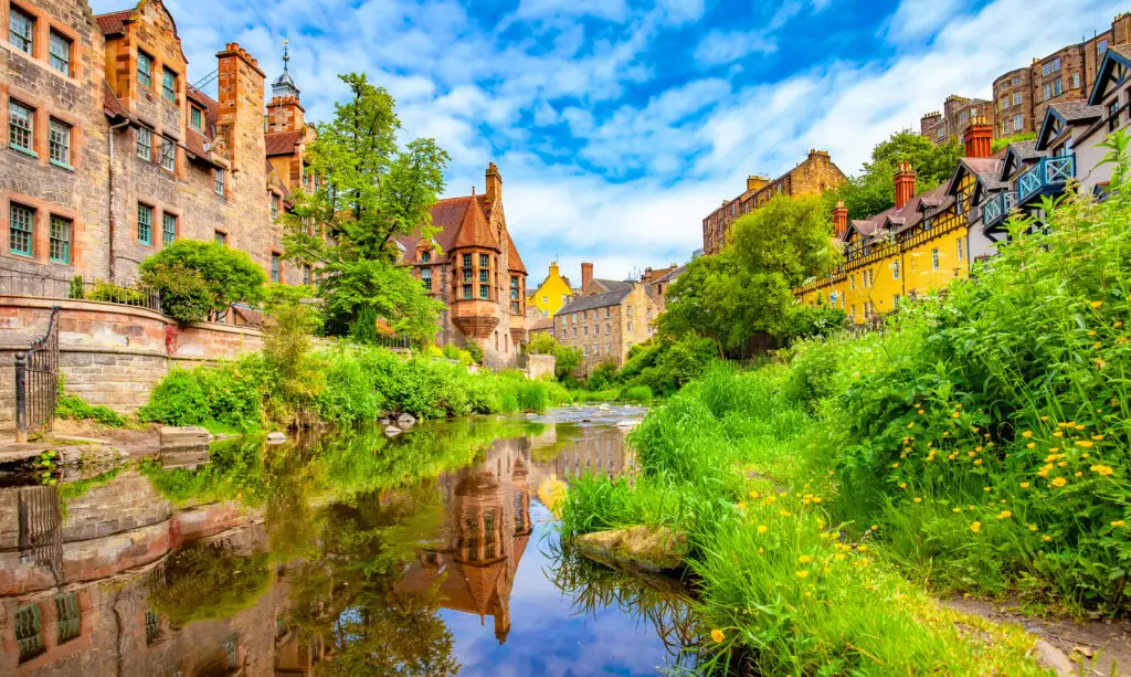 Colorful historic buildings along the Water of Leith in Dean Village, Edinburgh, Scotland, reflecting in the river on a bright summer day