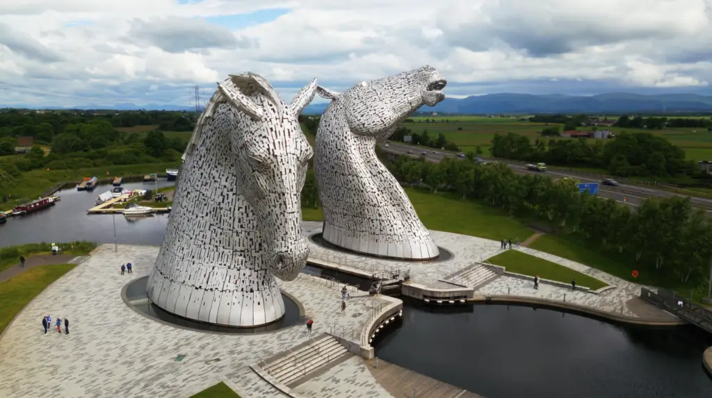 The Kelpies horse head sculptures in Falkirk, Scotland, towering over the canal with visitors walking around, a popular Scottish tourist attraction near The Helix Park.