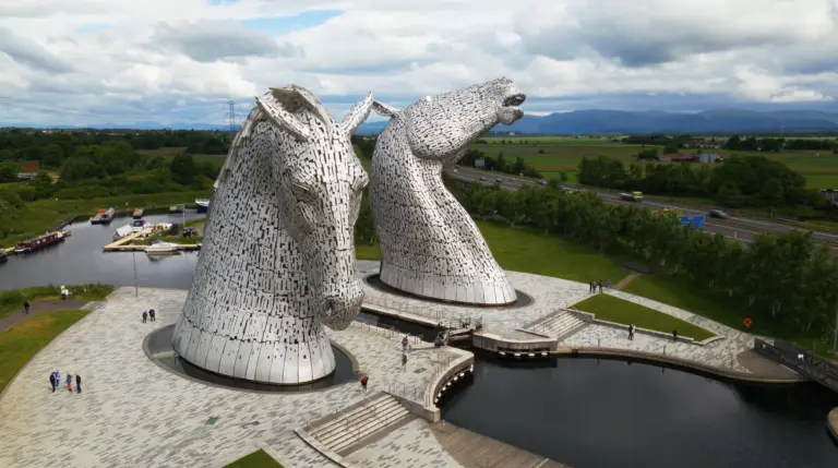 The Kelpies horse head sculptures in Falkirk, Scotland, towering over the canal with visitors walking around, a popular Scottish tourist attraction near The Helix Park.